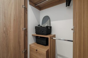 A wooden wardrobe with a mirror, a black woven basket, and a drawer.
