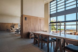 A spacious indoor area with a large table and chairs, a wooden accent wall, and large windows offering a view.