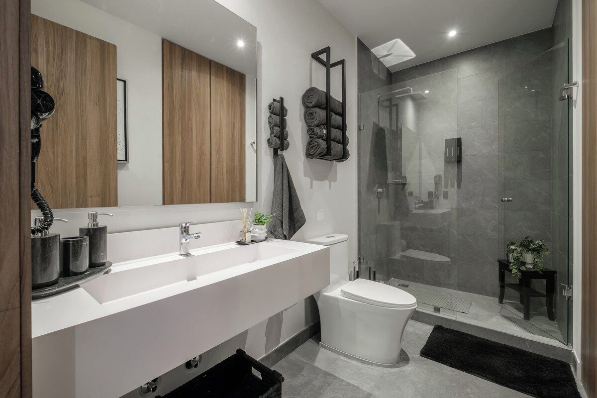 Un bagno moderno con lavandino bianco, servizi igienici e cabina doccia in vetro.