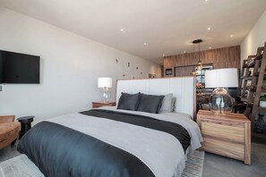A modern bedroom with a large bed, bedside tables, a TV, and a wooden wardrobe.