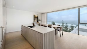 A modern kitchen with a large island, a dining area with a view of the ocean, and a spacious living area with a large window overlooking the sea.