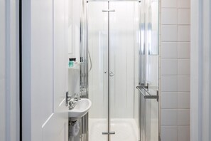 A modern bathroom with a glass shower enclosure, a white sink, and a mirror. - Tranquil Pontcanna Mews (Cardiff)