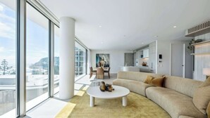 A modern living room with a large window, a round coffee table, and a beige sofa.