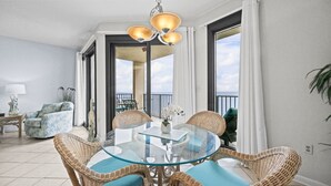 A balcony with a glass table and wicker chairs, a sofa, and a lamp. - Phoenix East 1205 1 Bedroom Condo (Orange Beach)