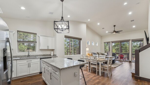 A spacious kitchen with a large island, white cabinetry, and a dining area with a table and chairs.