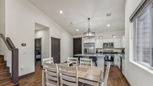 A modern kitchen with white cabinets, a central island, and a dining area with a wooden table and chairs.