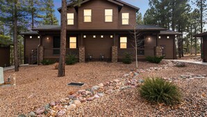 A two-story house with a dark brown exterior, multiple windows, and a stone foundation.