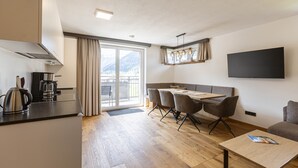 A modern kitchen with a kettle, a coffee maker, and a dining area with a table and chairs. - Amazing Apartment in Tyrol With Sauna (Lermoos)