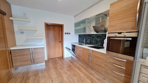 A modern kitchen with wooden cabinets, a stainless steel sink, and a built-in oven. - Wonderful Apartment Close to the ski Slope (Bad Kleinkirchheim)