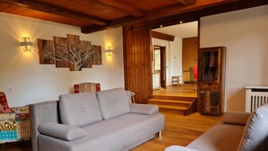 A living room with a grey sofa, wooden flooring, and a staircase leading to another room. - Wonderful Apartment Close to the ski Slope (Bad Kleinkirchheim)