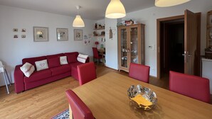 A living room with a red sofa, wooden dining table, and pendant lights. - Central Vacation Apartment With View (Bad Kleinkirchheim)