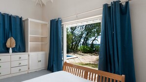 A bedroom with a bed, a wooden headboard, a white dresser with drawers, and a window with blue curtains. - Inch By Inch 3 Bedroom Home by Bluescape (Silver Sands)