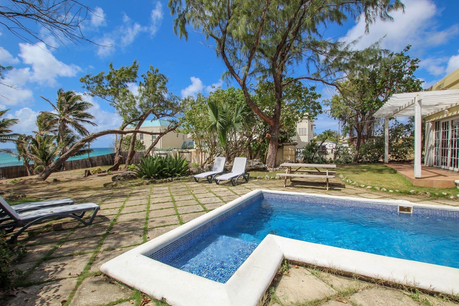 A backyard with a swimming pool, lounge chairs, and a pergola.