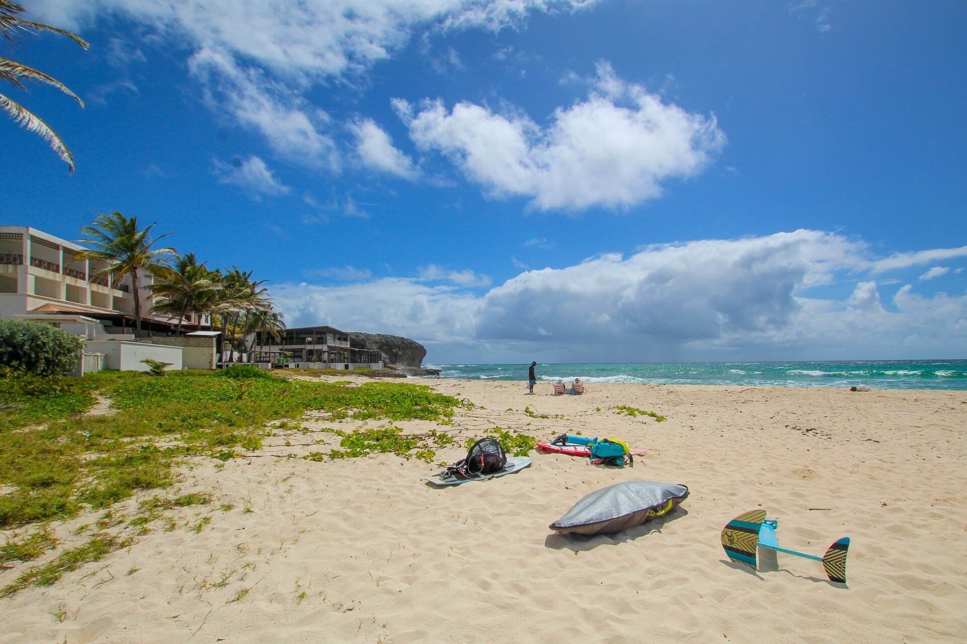 Une plage avec un bâtiment, des palmiers et un ciel dégagé.