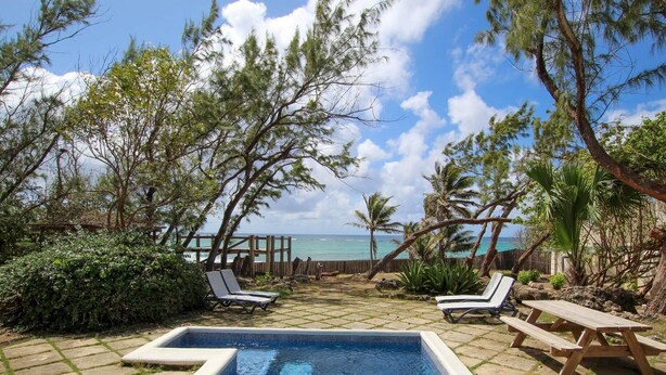 A swimming pool with lounge chairs and a wooden deck overlooking the ocean. - Inch By Inch 3 Bedroom Home by Bluescape (Silver Sands)