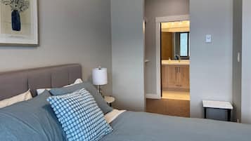 A bedroom with a bed, pillows, a bedside lamp, and a framed picture on the wall.