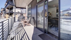 Ein modernes Gebäude mit einem Balkon, großen Schiebeglasfenstern und Blick auf eine verschneite Landschaft.
