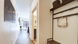 Ein Flur mit Holzboden, einer weißen Wand mit einem Zierpaneel und einem Regal mit Körben.