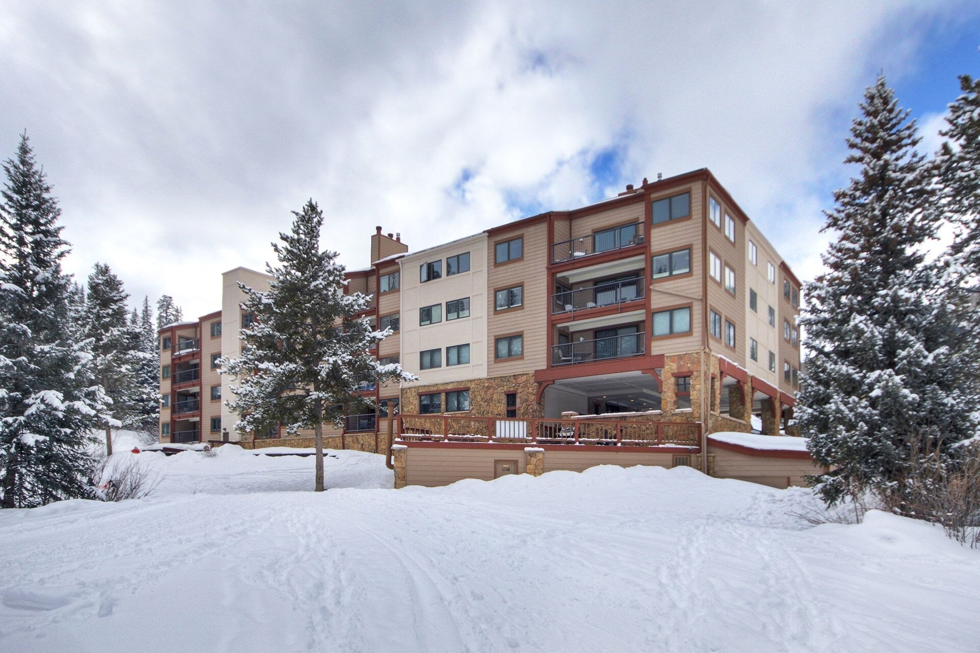 Un hotel de varios pisos con fachada de piedra, balcones y un paisaje cubierto de nieve.