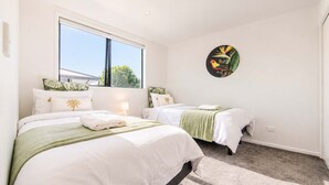 Habitación de hotel con dos camas, un ventanal grande y un adorno de pared con motivos tropicales.