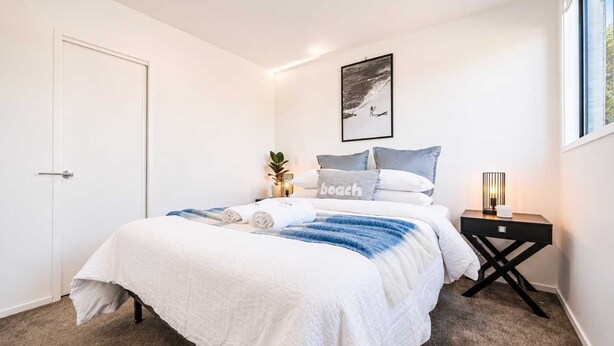 Ein Schlafzimmer mit einem Bett, einem Nachttisch, einem Wandbild und einer Tür.
