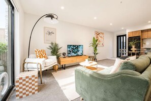 A modern living room with a sofa, a coffee table, a TV, and a lamp.