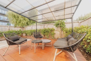 A covered patio with wicker furniture and a transparent roof.