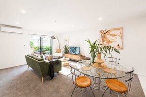 A modern living room with a sofa, coffee table, and a glass dining table with chairs.