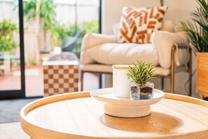 A round wooden table with a white candle and a small plant in a glass container.