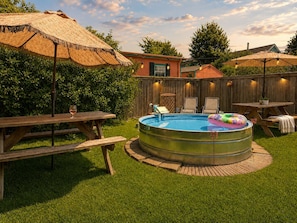 A backyard with a circular swimming pool, picnic tables, and a thatched umbrella. - "La Lune Noire NOLA" (New Orleans)