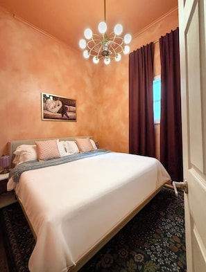 A hotel room with a large bed, a chandelier, a painting on the wall, and a view of the outdoors. - "La Lune Noire NOLA" (New Orleans)