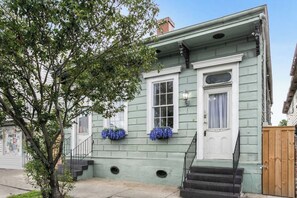 A two-story house with a front porch, a staircase, and a small garden area.
