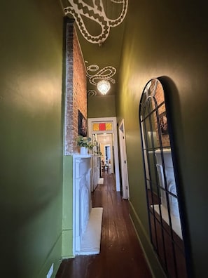 A hallway with a brick wall, a white fireplace, and a door leading to another room. - "La Lune Noire NOLA" (New Orleans)