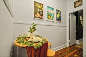 A dining area with a table set for two, a vase with flowers, and three vintage posters on the wall. - Delightful Design & Cowboy Pool by French Quarter (New Orleans)