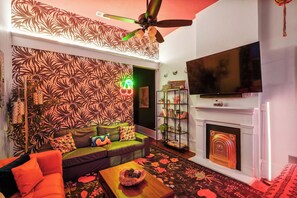 Una sala de estar con una pared estampada, un sofá, una mesa de centro, una chimenea y un televisor.