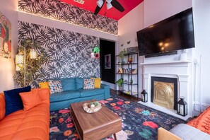 A living room with a sofa, a coffee table, a fireplace, a TV, and a bookshelf. - Delightful Design & Cowboy Pool by French Quarter (New Orleans)