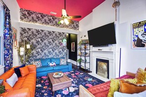 A living room with a blue sofa, orange couch, and a fireplace. - Delightful Design & Cowboy Pool by French Quarter (New Orleans)