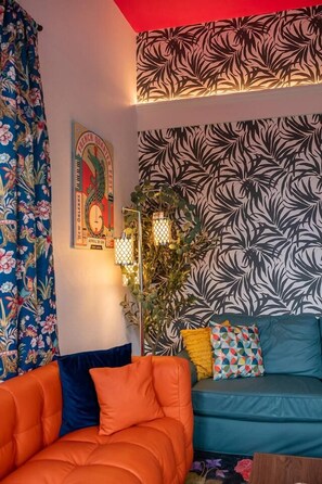 Une pièce avec un canapé, un mur à motifs et une affiche.