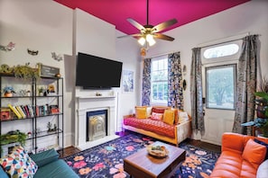 A living room with a fireplace, a sofa, a television, and a ceiling fan. - Delightful Design & Cowboy Pool by French Quarter (New Orleans)