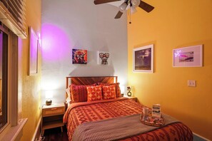 A bedroom with a bed, a nightstand, a lamp, and wall art. - Delightful Design & Cowboy Pool by French Quarter (New Orleans)