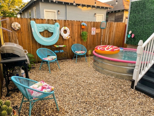 Un patio trasero con piscina, flotadores inflables y una parrilla.