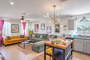 A modern living room with a sofa, coffee table, and a dining area with a kitchen counter. - Spacious Retreat by FQ | Mini-Pool | EV Parking (New Orleans)