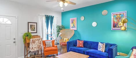 A living room with a blue sofa, orange armchair, and a ceiling fan.