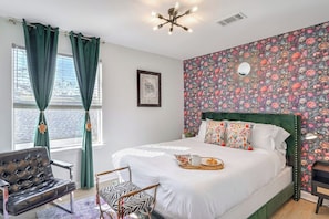A bedroom with a bed, a chair, a small table with a tray, and a decorative mirror. - Spacious Retreat by FQ | Mini-Pool | EV Parking (New Orleans)