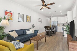 Ein modernes Wohnzimmer mit Sofa, Couchtisch und einem Essbereich mit Stühlen und Tisch.