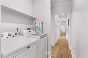 A laundry area with two white washing machines, a drying rack, and a wooden floor.