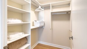 A walk-in closet with multiple shelves, a hanging rack, and a basket.
