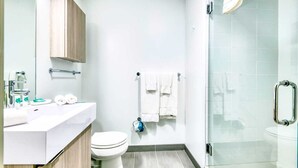 Une salle de bain moderne avec un lavabo blanc, des toilettes et une douche à parois de verre.