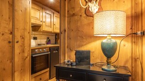 Un intérieur en bois comprenant un coin cuisine, avec des placards, une cuisinière et une lampe sur un bureau.