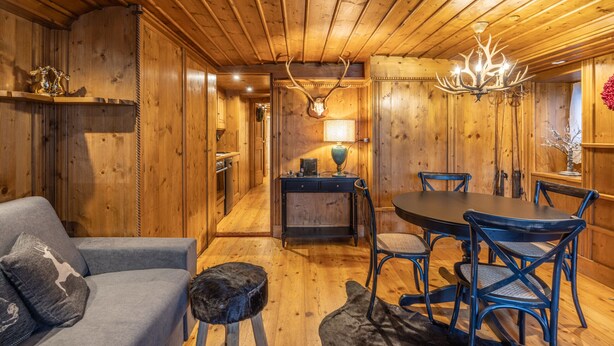Un intérieur en bois comprenant une table à manger, des chaises, un canapé et un lustre.
